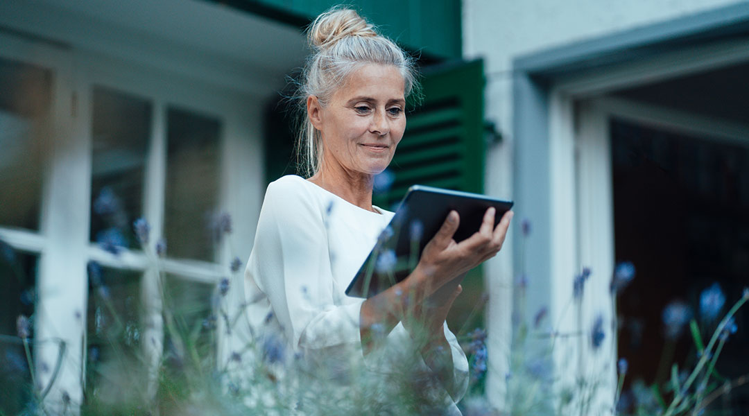 an older lady with a high bun in her garden looking down at her ipad an older lady with a high bun in her garden looking down at her ipad